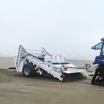 Traktor pencuci pantai alkali yang ditarik untuk menyaring puing-puing dari pasir kering atau basah